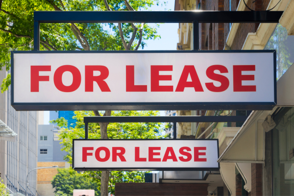 two "For Lease" signs hanging outside a building
