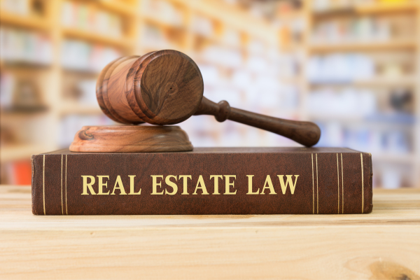 large book titled 'real estate law' with gavel on top of it