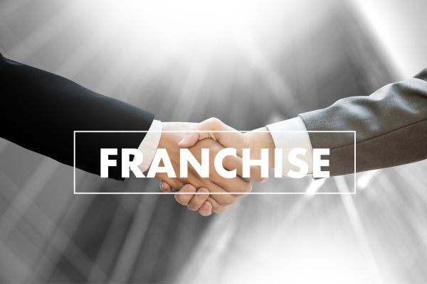two men in suits shaking hands with the word "franchise" in the foreground
